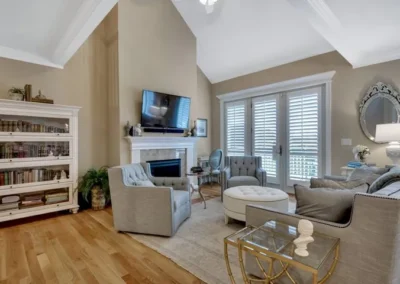 Spacious living room with vaulted ceiling, elegant furniture, large windows, and cozy fireplace.