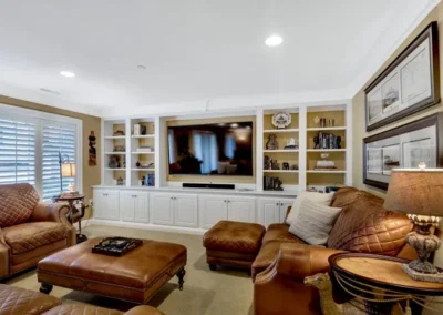 Cozy family room with leather sofas, large TV, built-in shelves, and warm lighting.