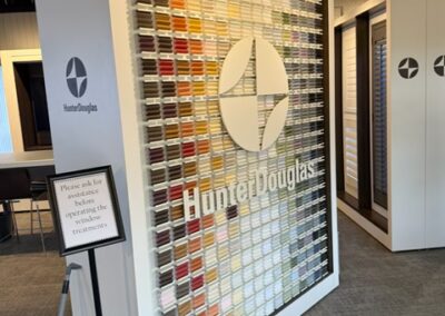 Hunter Douglas display featuring colorful window treatment samples in showroom setting with modern lighting.